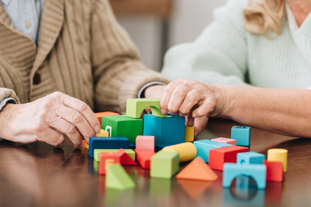 Zwei Personen spielen in Gelsenkirchen gemeinsam mit bunten Holzklötzen zur Demenzbetreuung